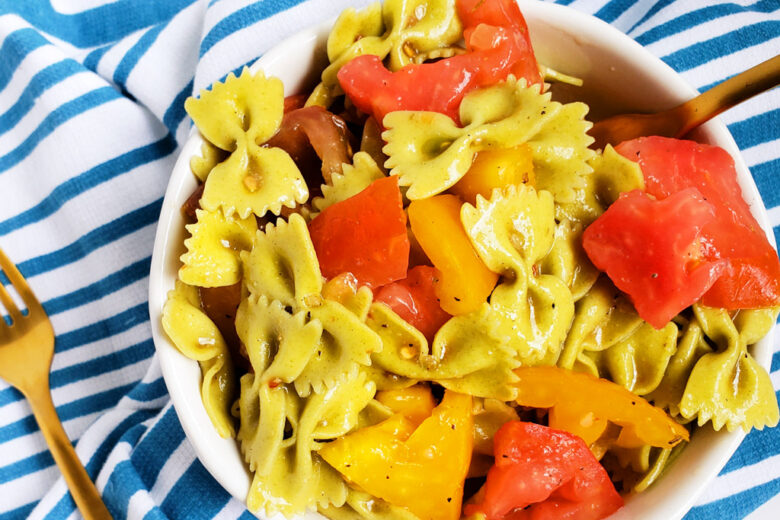 Easy Heirloom Tomato Bow-Tie Pasta with spinach bow-tie pasta in a white bowl on a blue and white striped towel