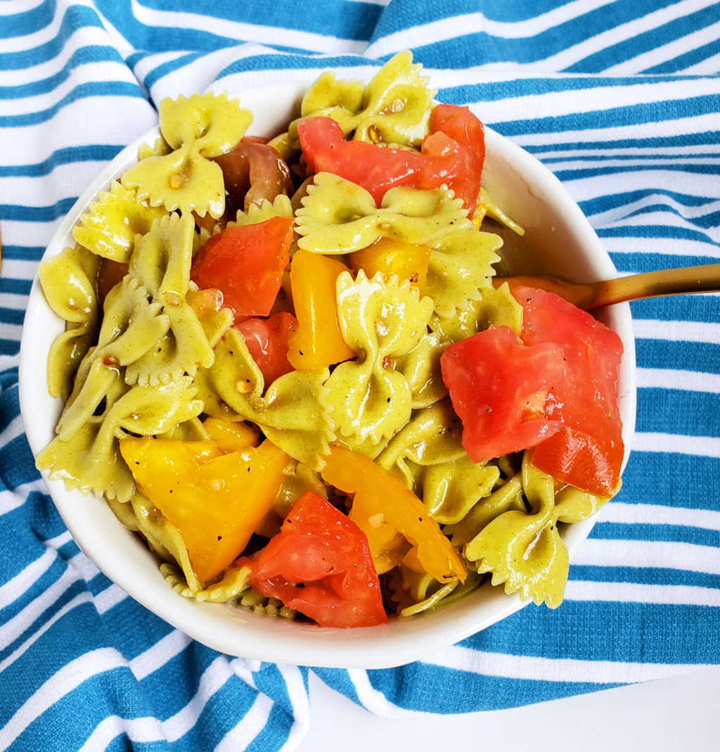 Easy Heirloom Tomato Bow-Tie Pasta with spinach bow-tie pasta in a white bowl on a blue and white striped towel