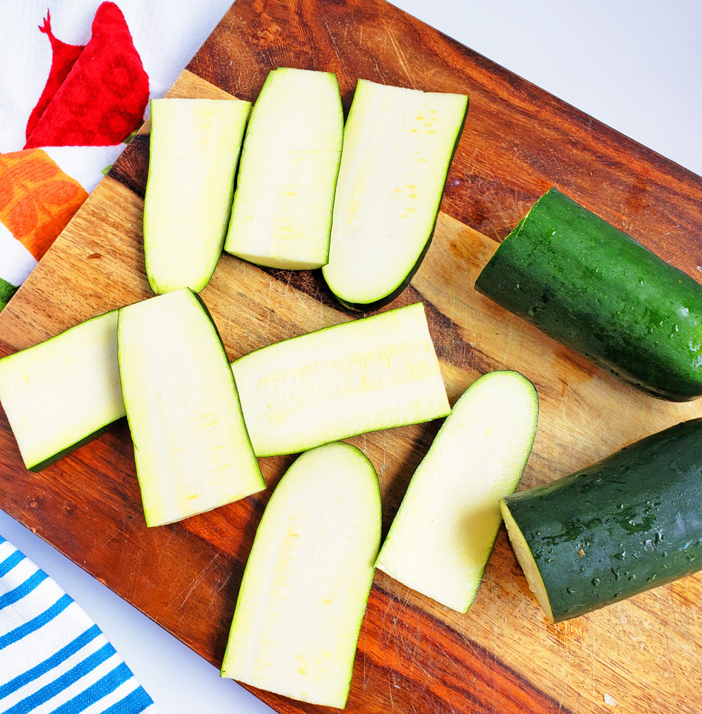 Mini Zucchini Pizza Boats, sliced zucchini topped with mozzarella cheese and mini pepperoni on a cookie sheet