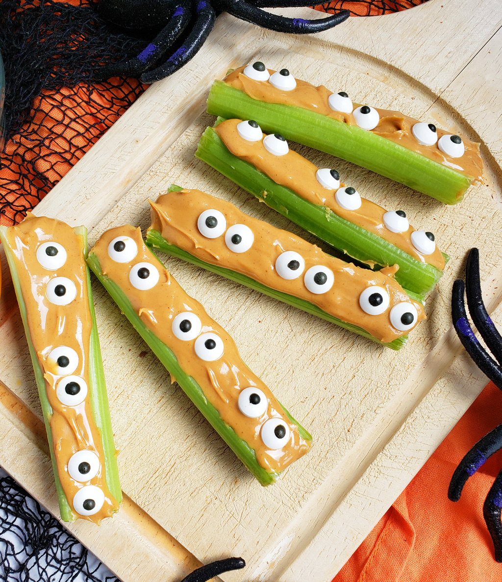 spooky monsters on a log made with celery sticks, peanut butter and candy eyes