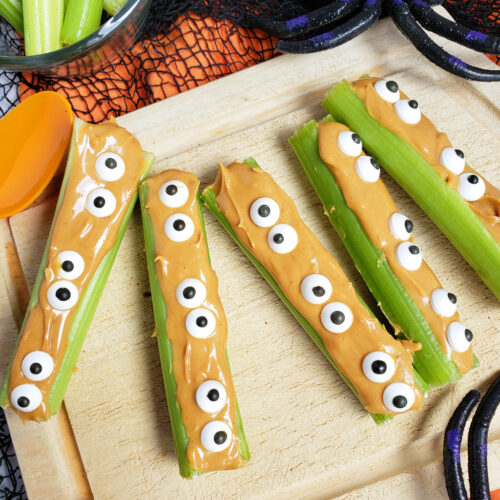 spooky monsters on a log made with celery sticks, peanut butter and candy eyes