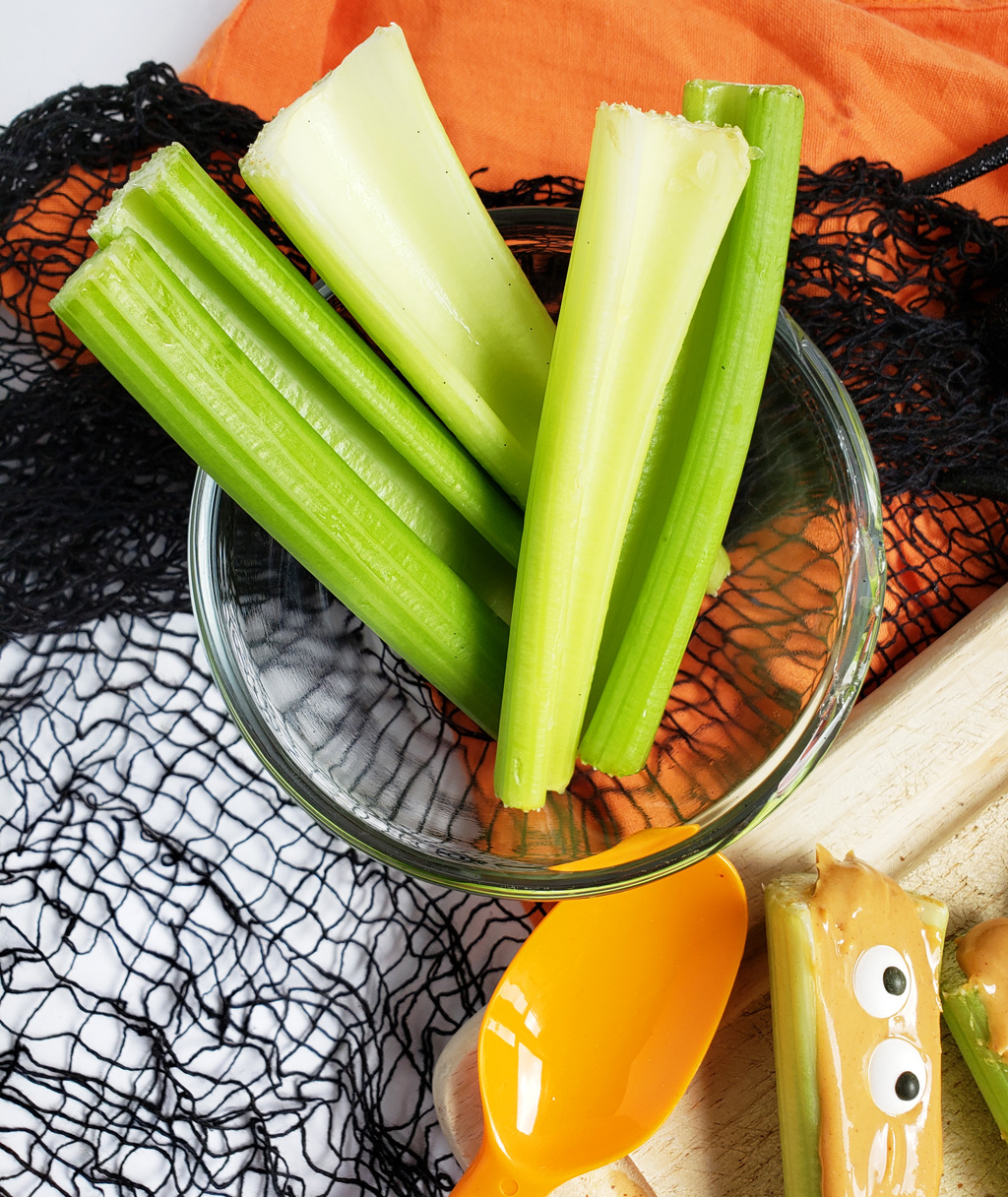 spooky monsters on a log made with celery sticks, peanut butter and candy eyes