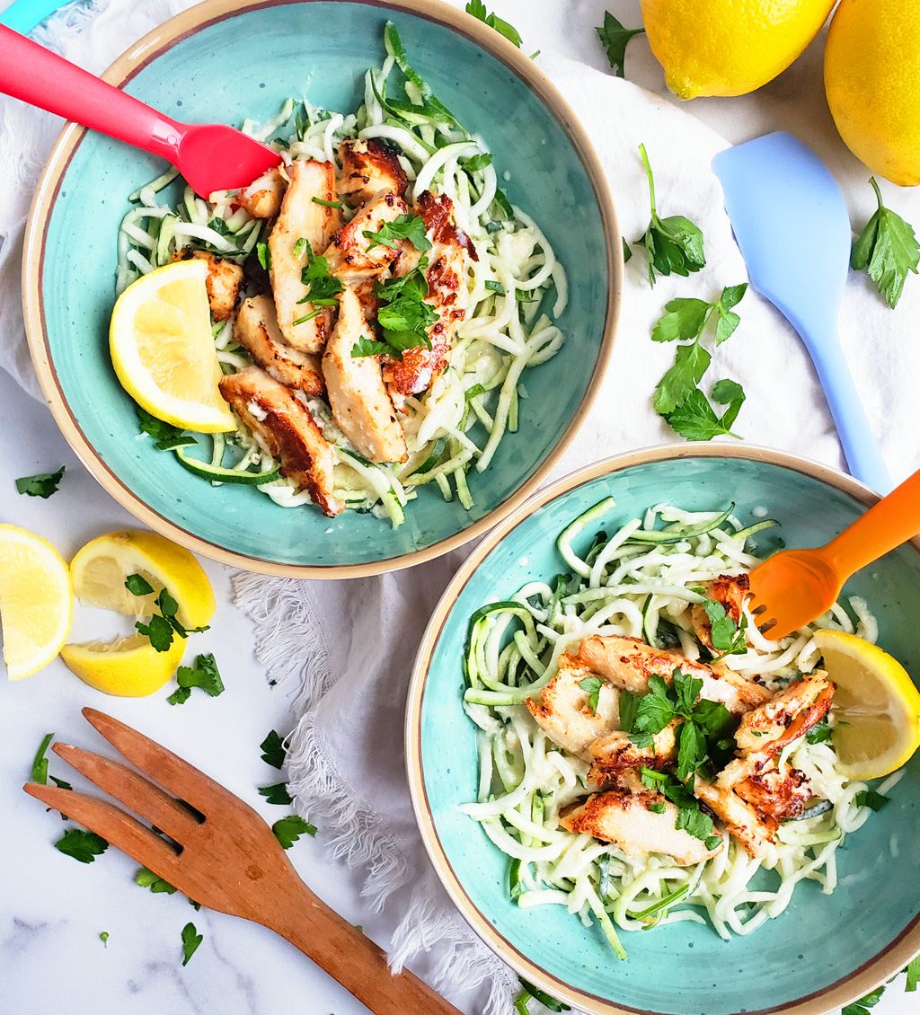 Creamy Lemony Chicken & Zoodles in a blue bowl with zucchini noodles, parsley and lemon slices. Perfect for kids.