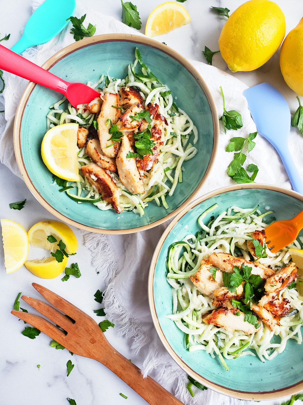 Creamy Lemony Chicken & Zoodles in a blue bowl with zucchini noodles, parsley and lemon slices. Perfect for kids.