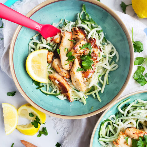 Creamy Lemony Chicken & Zoodles in a blue bowl with zucchini noodles, parsley and lemon slices. Perfect for kids.