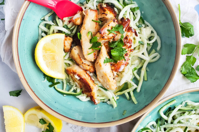 Creamy Lemony Chicken & Zoodles in a blue bowl with zucchini noodles, parsley and lemon slices. Perfect for kids.