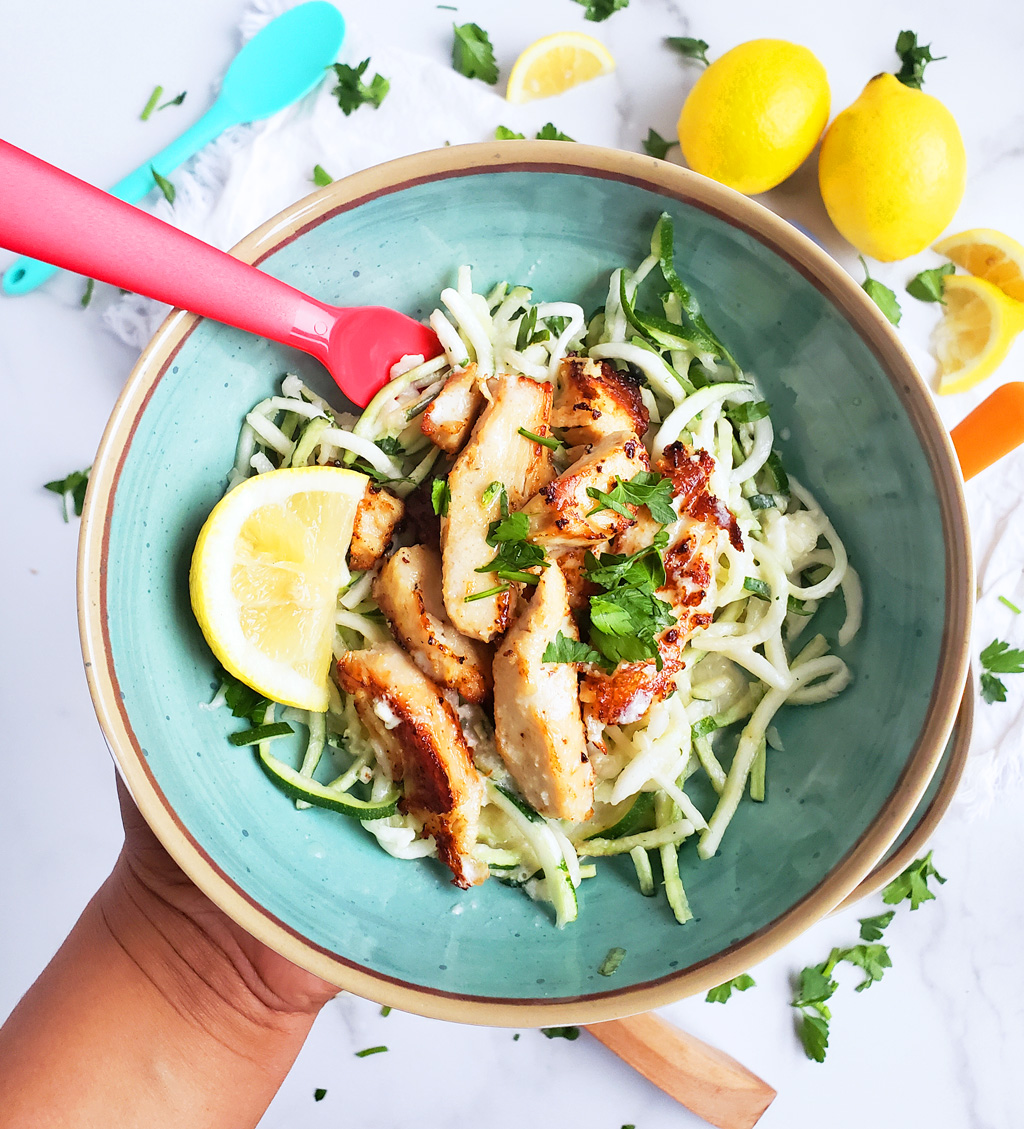 Creamy Lemony Chicken & Zoodles in a blue bowl with zucchini noodles, parsley and lemon slices. Perfect for kids.