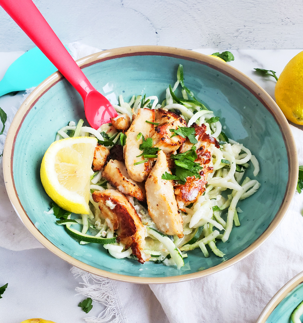 Creamy Lemony Chicken & Zoodles in a blue bowl with zucchini noodles, parsley and lemon slices. Perfect for kids.