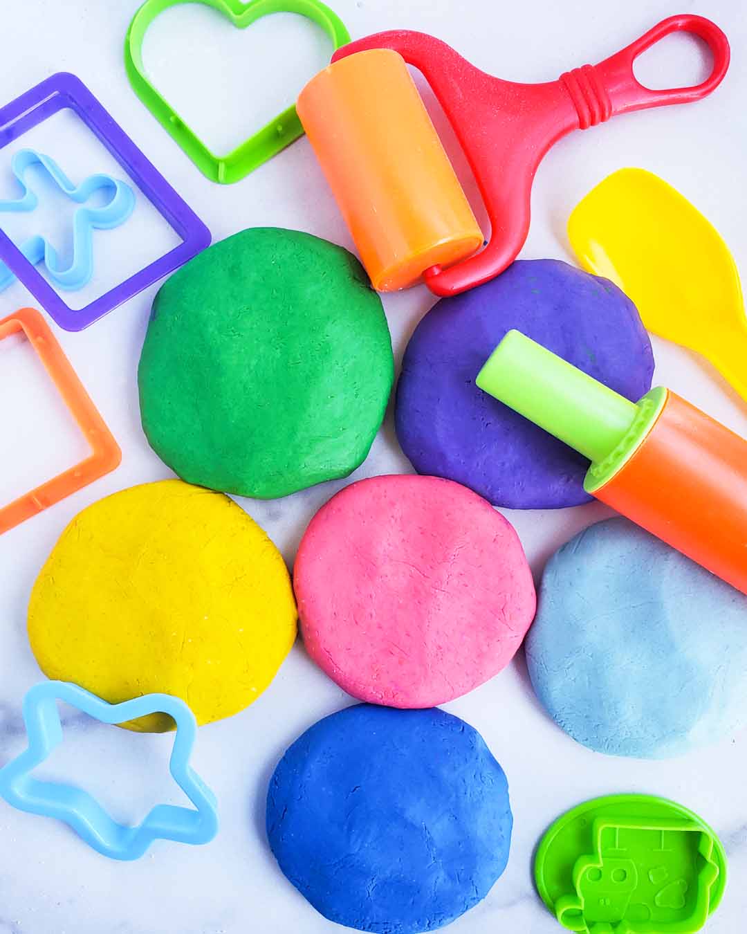 Easy No-Cook DIY Playdough, made with no cream of tartar, and no cooking required. The easiest playdough recipe ever. Different color playdough and utensils. #sensoryactivities #indooractivitiesforkids #indooractivities #homemadeplaydough #playdoh