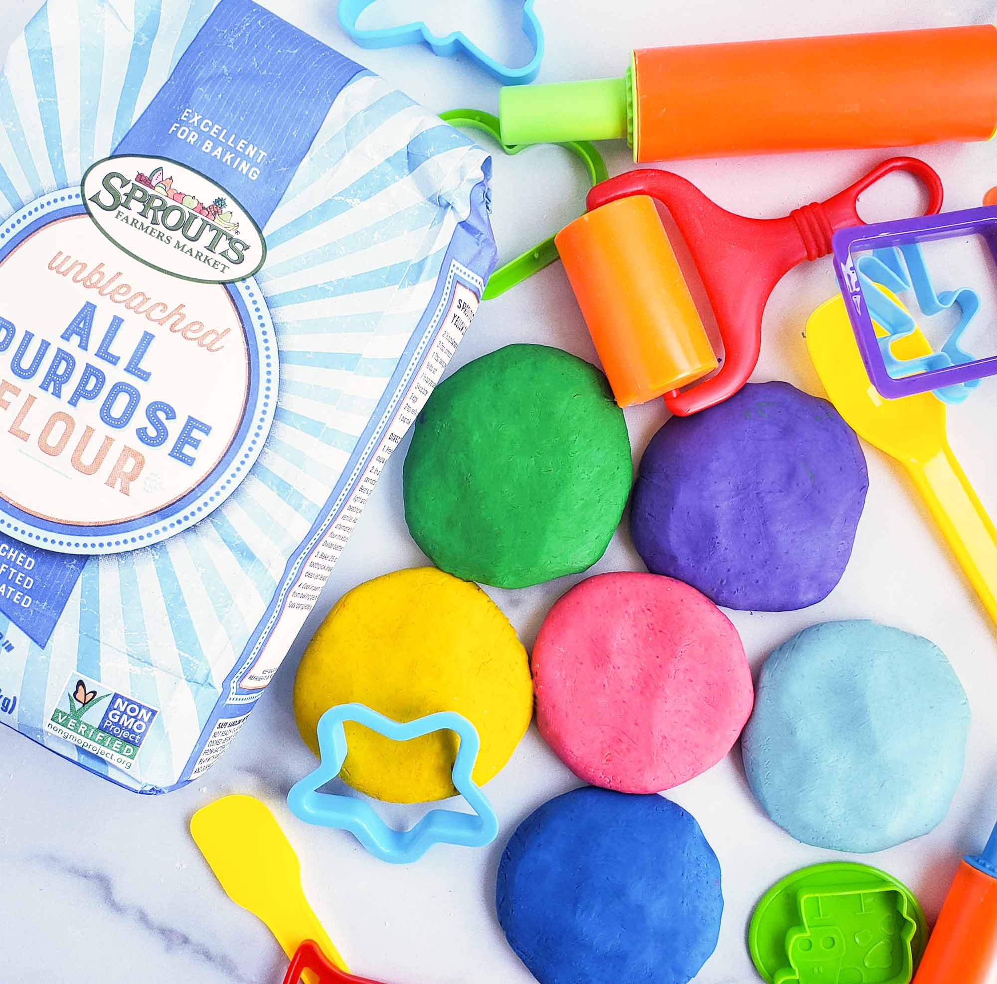 Easy No-Cook DIY Playdough, made with no cream of tartar, and no cooking required. The easiest playdough recipe ever. Different color playdough and utensils. #sensoryactivities #indooractivitiesforkids #indooractivities #homemadeplaydough #playdoh