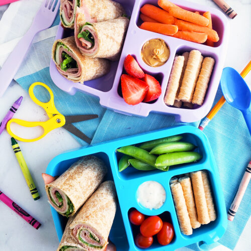 Bento box filled and arranged beautifully with fruits, veggies, whole wheat ham and cheese wraps. Healthy bento lunch ideas for kids. Littleeatsandthings.com