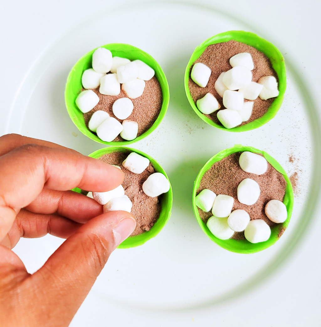 Green Grinch hot chocolate bombs with white chocolate drizzled on top, with Christmas sprinkles. DIY Hot chocolate bomb recipe. www.littleeatsandthings.com