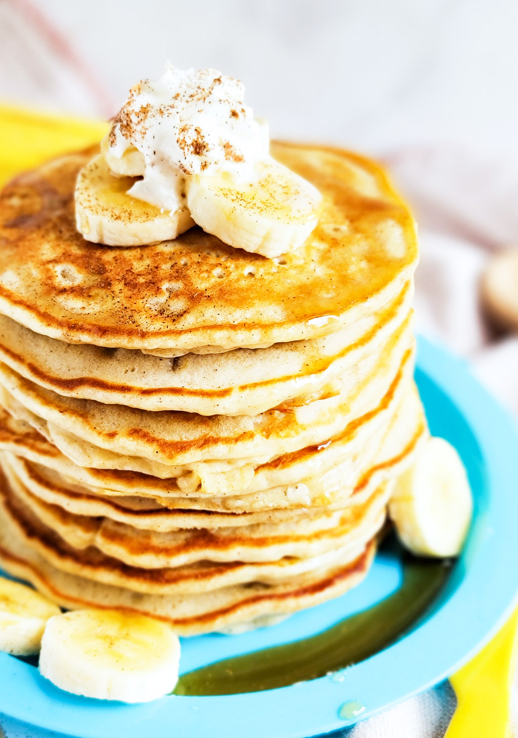 banana pancakes with syrup topped with sliced bananas, whipped cream, and cinnamon  littleeatsandthings.com