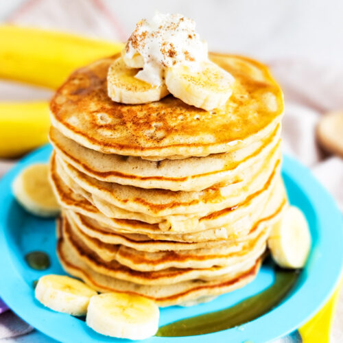 banana pancakes with syrup topped with sliced bananas, whipped cream, and cinnamon littleeatsandthings.com