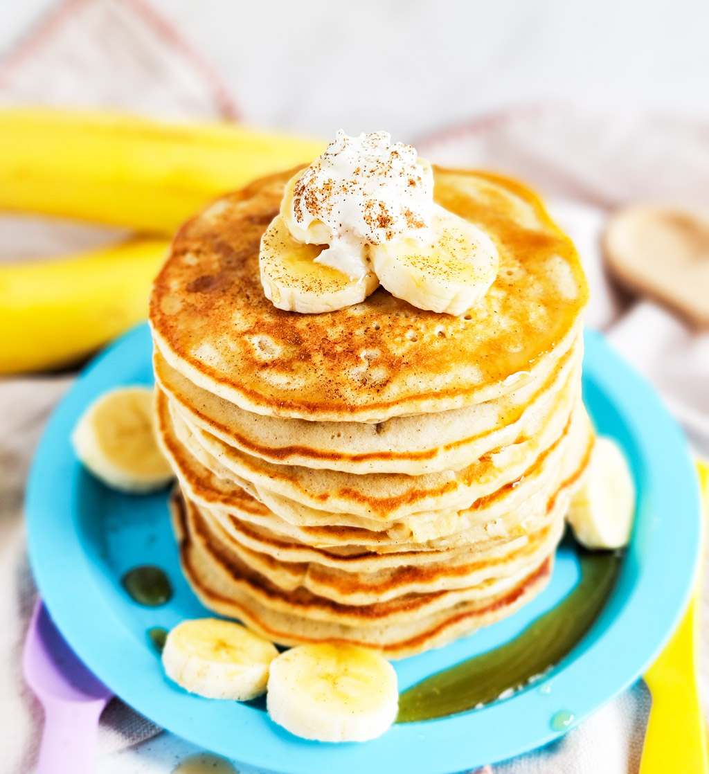 banana pancakes with syrup topped with sliced bananas, whipped cream, and cinnamon  littleeatsandthings.com