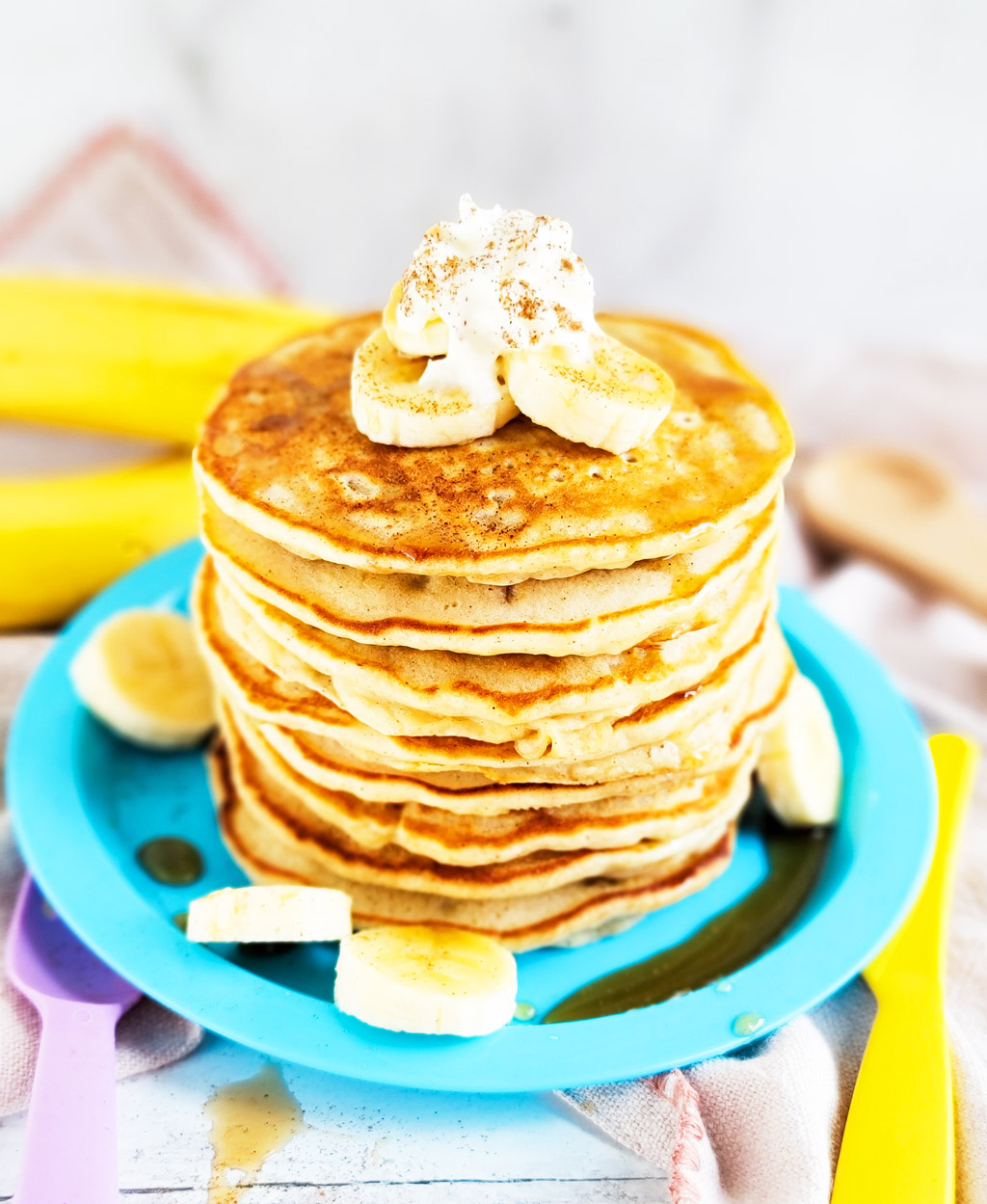 banana pancakes with syrup topped with sliced bananas, whipped cream, and cinnamon  littleeatsandthings.com