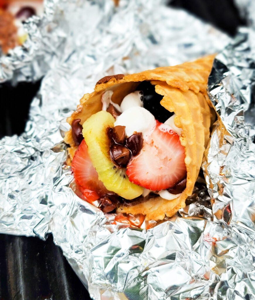 fire up the grill and make these delicious Fruity Campfire Cones made with waffle cones stuffed with marshmallows, chocolate chips, strawberry, kiwi, and blueberries littleeatsandthings.com