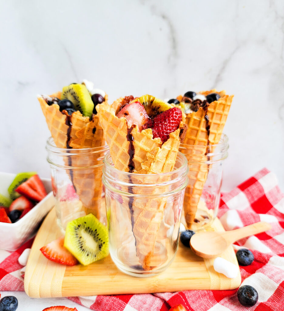 fire up the grill and make these delicious Fruity Campfire Cones made with waffle cones stuffed with marshmallows, chocolate chips, strawberry, kiwi, and blueberries littleeatsandthings.com