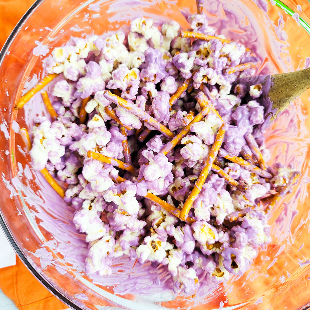 Spooky Halloween Popcorn Mix for the kids made with purple and orange white chocolate, pretzels, and candy eyeballs with black plastic spiders. beautifuleatsandthings.com