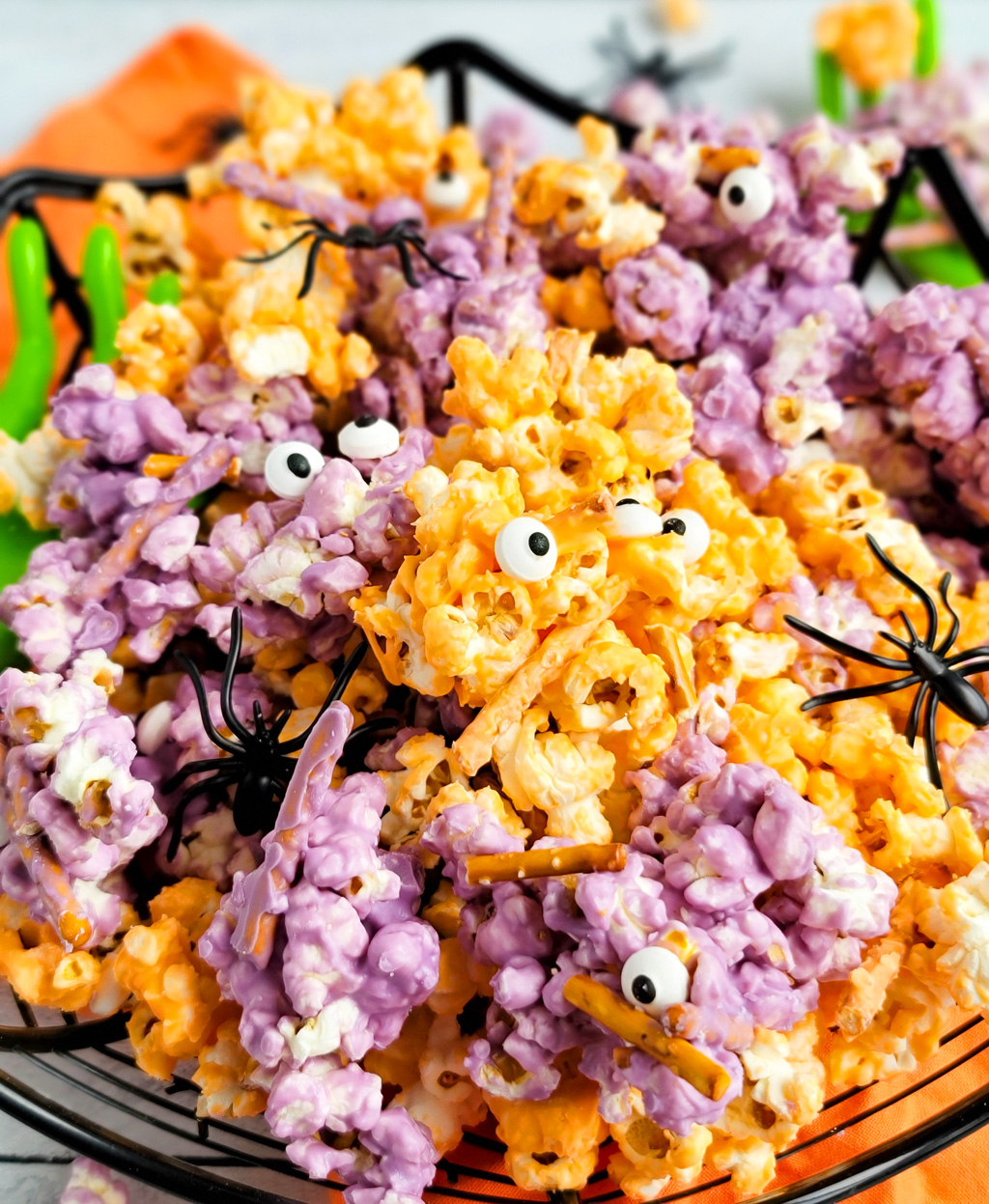 Spooky Halloween Popcorn Mix for the kids made with purple and orange white chocolate, pretzels, and candy eyeballs with black plastic spiders. beautifuleatsandthings.com