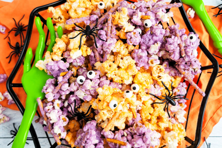 Spooky Halloween Popcorn Mix for the kids made with purple and orange white chocolate, pretzels, and candy eyeballs with black plastic spiders. beautifuleatsandthings.com