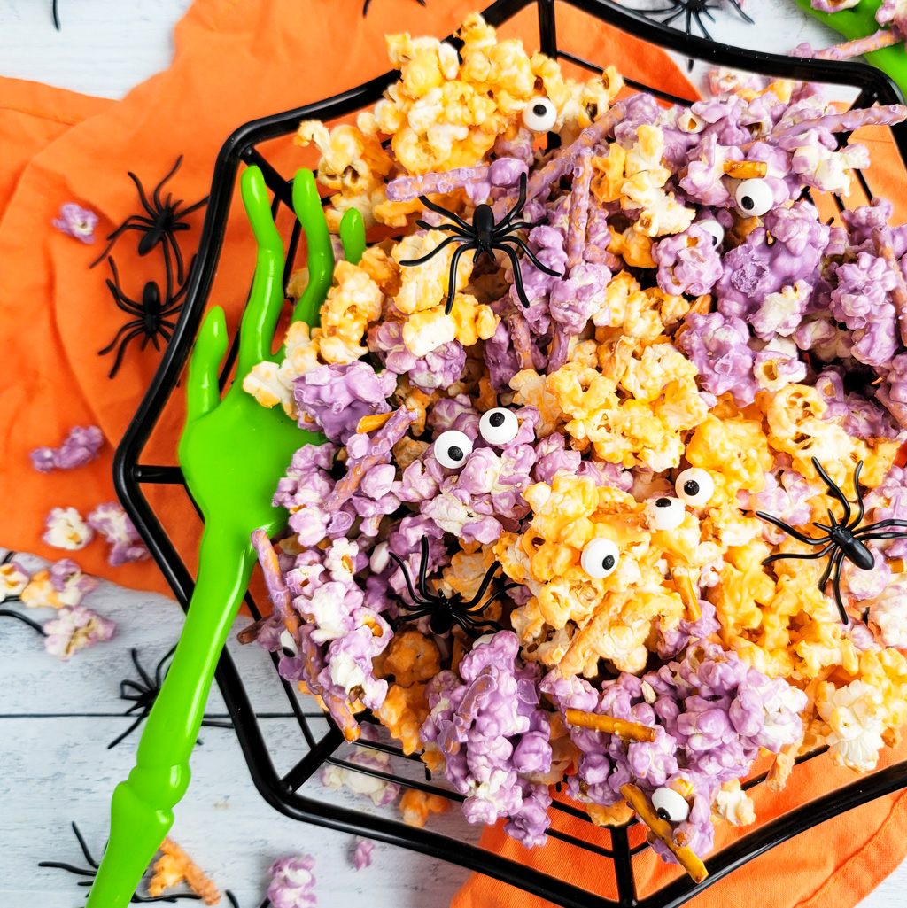 Spooky Halloween Popcorn Mix for the kids made with purple and orange white chocolate, pretzels, and candy eyeballs with black plastic spiders. beautifuleatsandthings.com