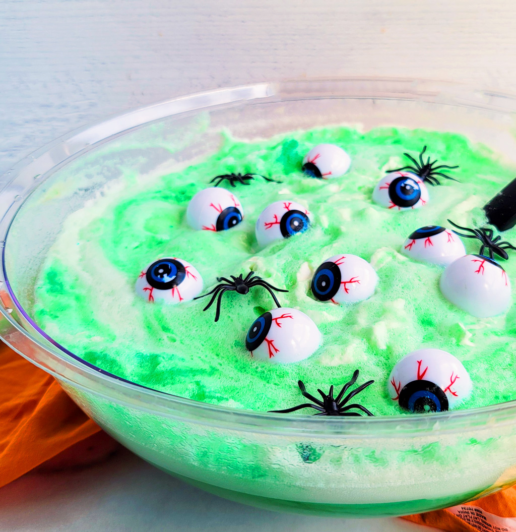 Try this Spooky Green Halloween Punch; green punch in a glass with plastic eyeballs and spiders and a purple straw littleeatsandthings.com