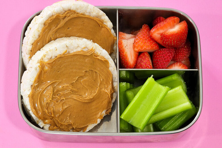 3 Kid-Approved Vegan Lunch Box Ideas in a bento box, rice cakes with peanut butter, celery sticks, strawberries, littleeatsandthings.com