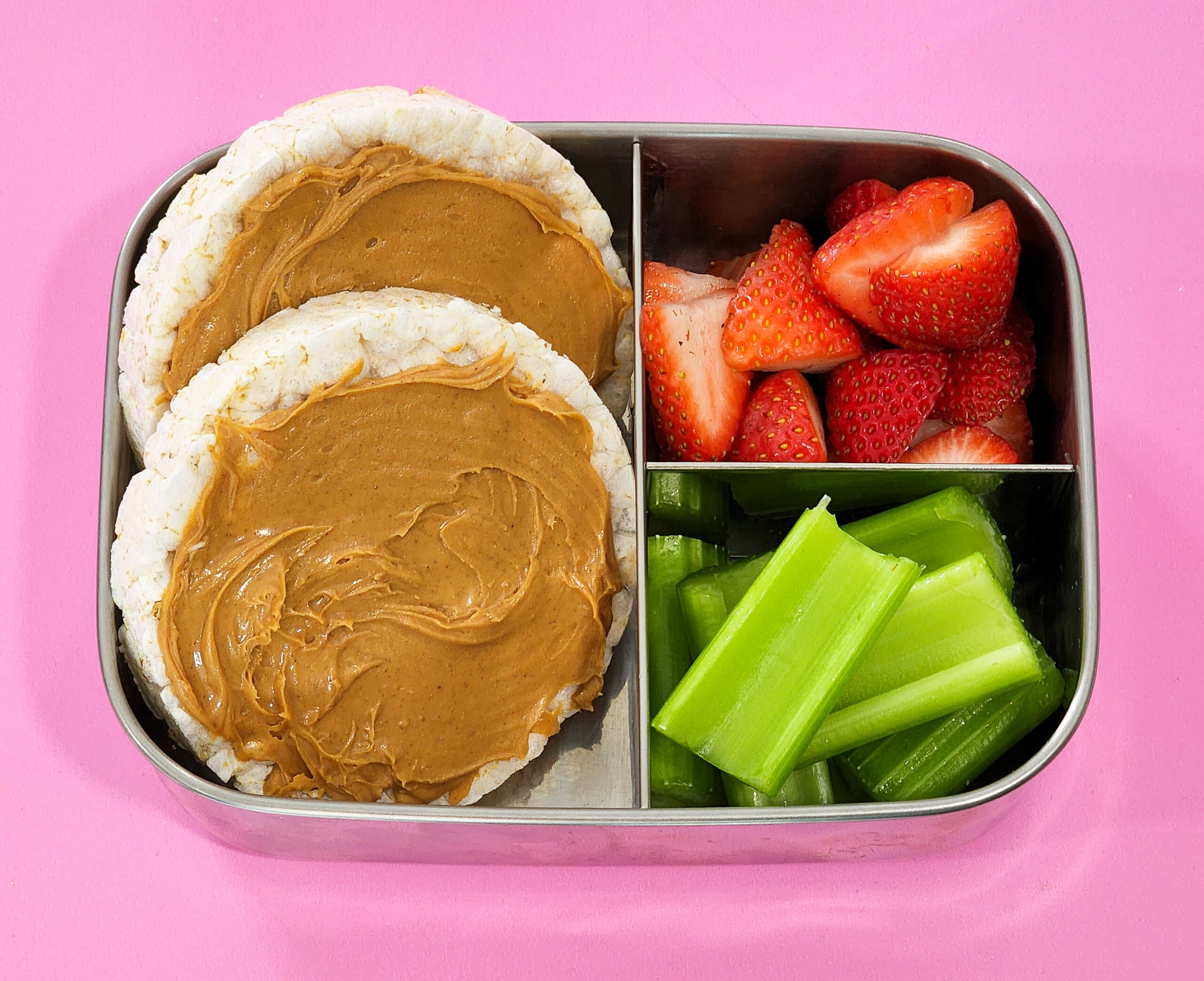 3 Kid-Approved Vegan Lunch Box Ideas in a bento box, rice cakes with peanut butter, celery sticks, strawberries, littleeatsandthings.com