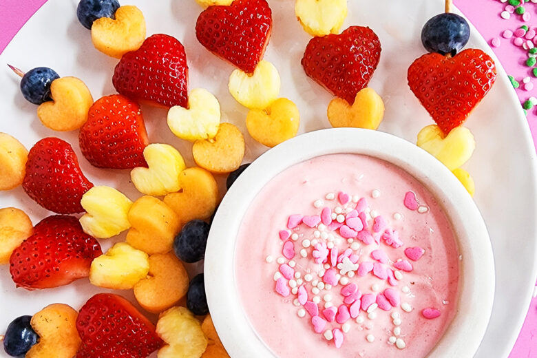 heart-shaped fruit skewers on a white plate on a pink surface for Valentine's Day littleeatsandthings.com